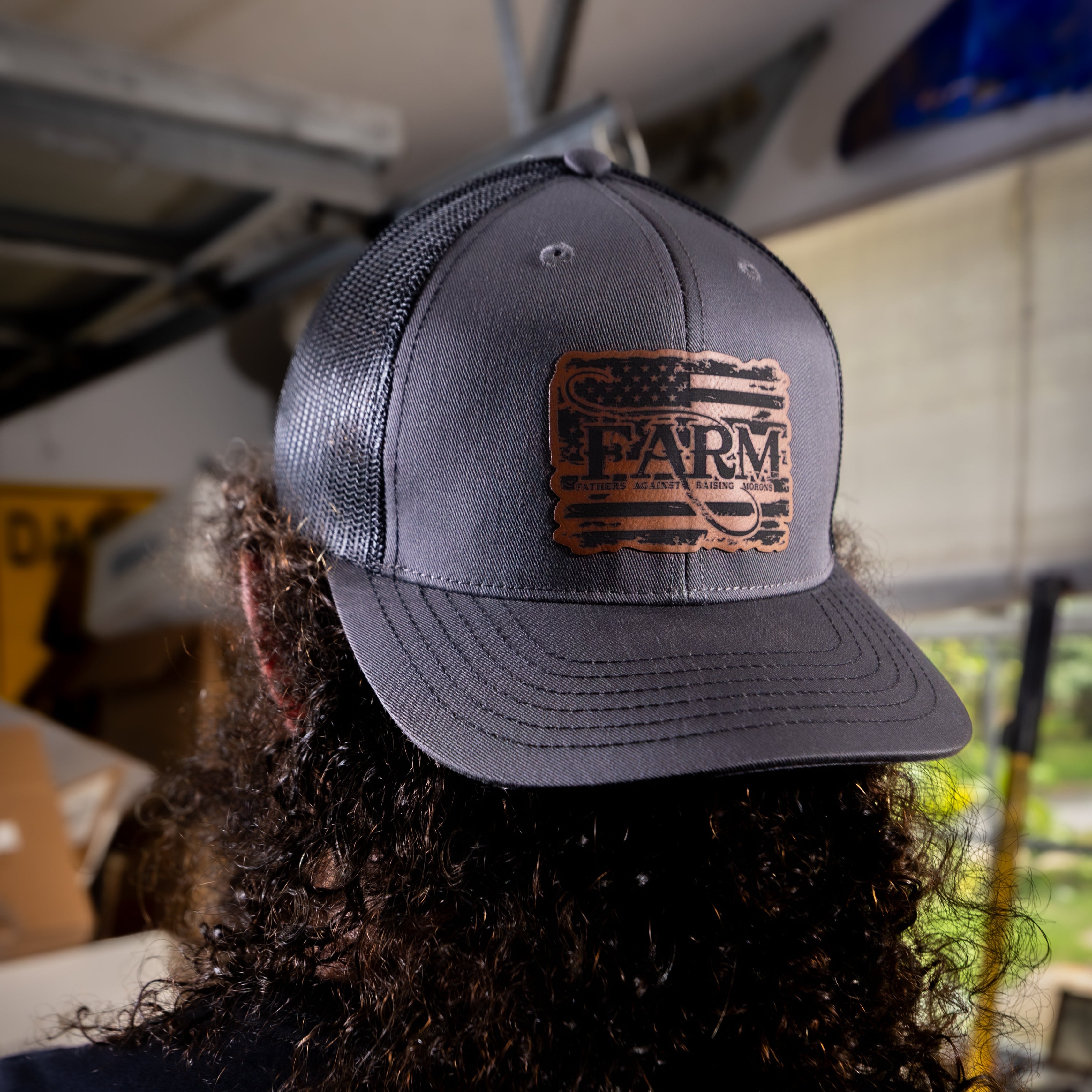 Person wearing a gray cap with a leather patch labeled 'FARM' in an indoor setting.