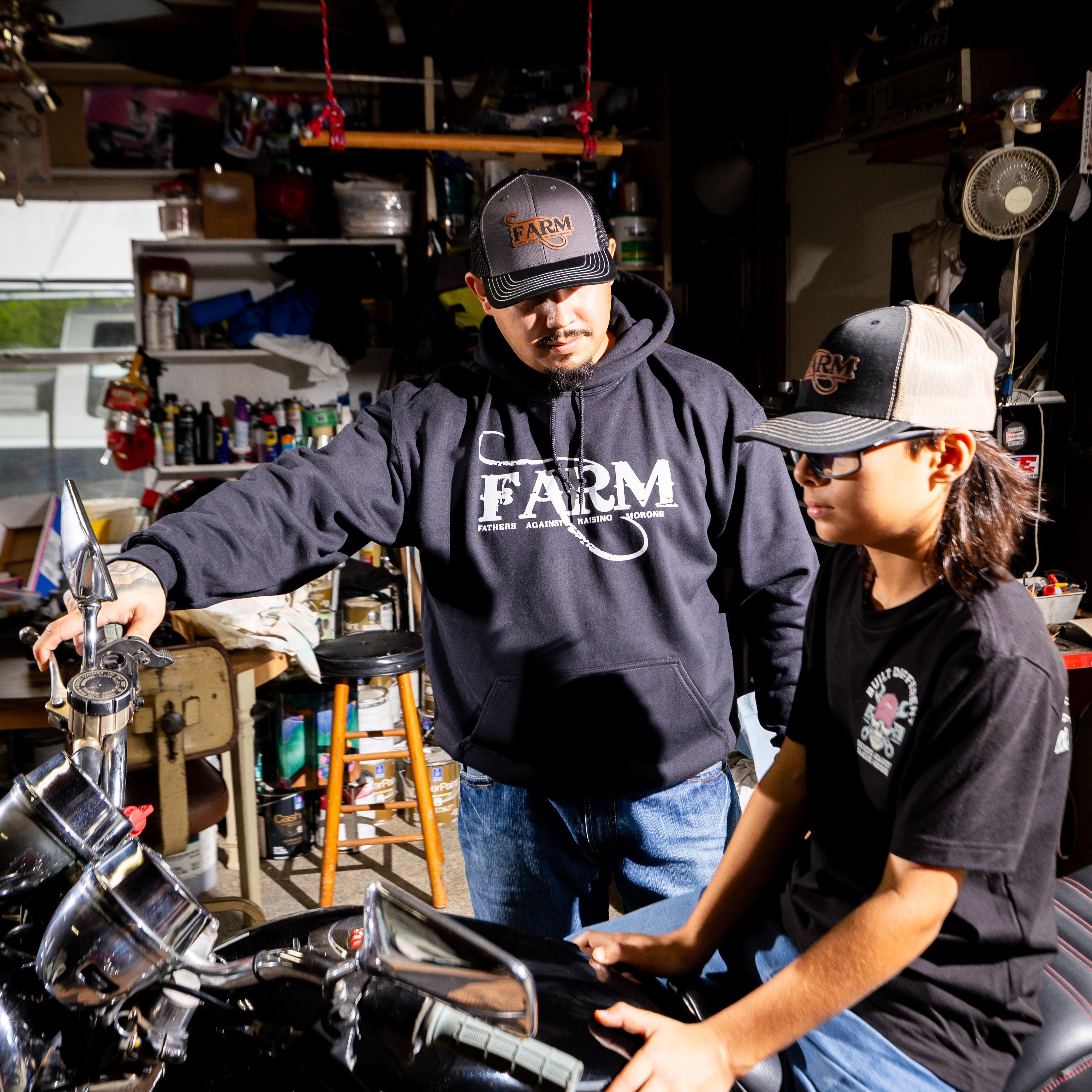 FARM black hoodie and black charcoal black hat with josh teaching ryder about bike